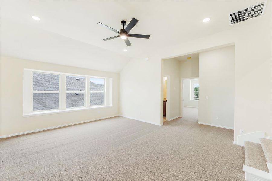 Empty bedroom with vaulted ceiling, ceiling fan, carpet flooring, and large windows Empty bedroom with vaulted ceiling, ceiling fan, carpet flooring, and large windows