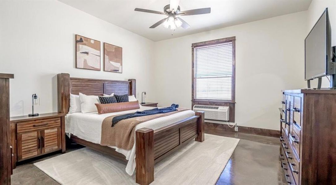 Bedroom with baseboards, ceiling fan, and finished concrete floors Bedroom with baseboards, ceiling fan, and finished concrete floors