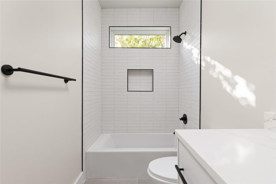 Clean lines and vertical wall tile define this sleek bathroom featuring a deep soaking tub.