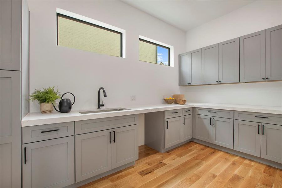 Kitchen with light hardwood / wood-style flooring, gray cabinetry, and sink