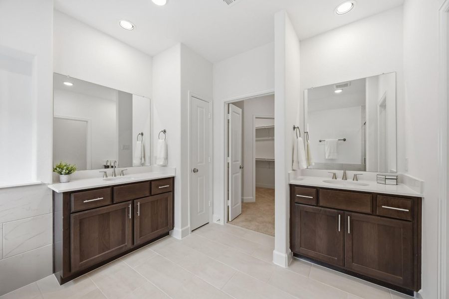 Spa-like Splendor: Dual vanities, a roomy linen closet, and a secluded water closet are set amid abundant space for an everyday spa experience right at home.