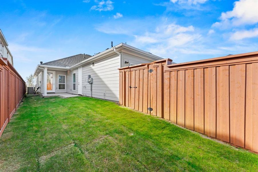 Back of property with a lawn and central AC