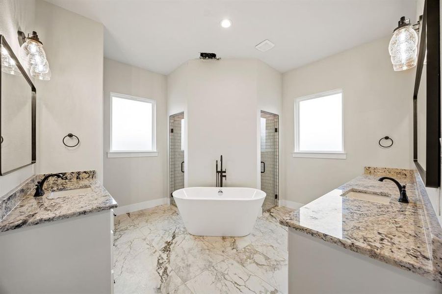Full bathroom with a shower stall, two vanities, a freestanding tub, healthy amount of natural light, and recessed lighting Full bathroom with a shower stall, two vanities, a freestanding tub, healthy amount of natural light, and recessed lighting