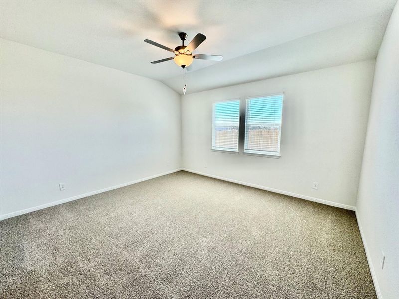 Empty room featuring carpet floors, lofted ceiling, and ceiling fan Empty room featuring carpet floors, lofted ceiling, and ceiling fan