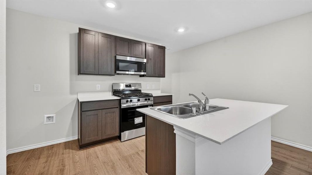Modern kitchen featuring dark wood-finish cabinetry, stainless steel appliances, a gas range, and wood-finish flooring