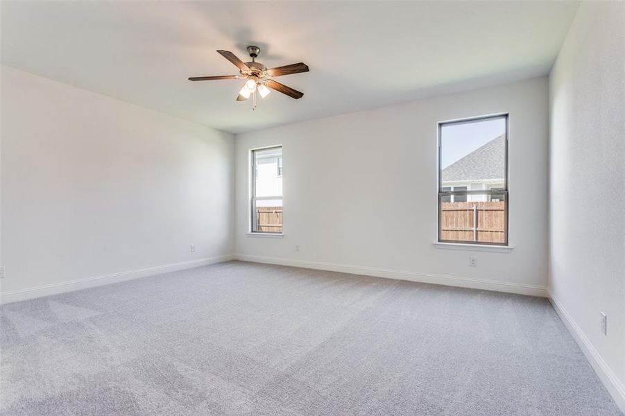 Carpeted spare room with a wealth of natural light and ceiling fan