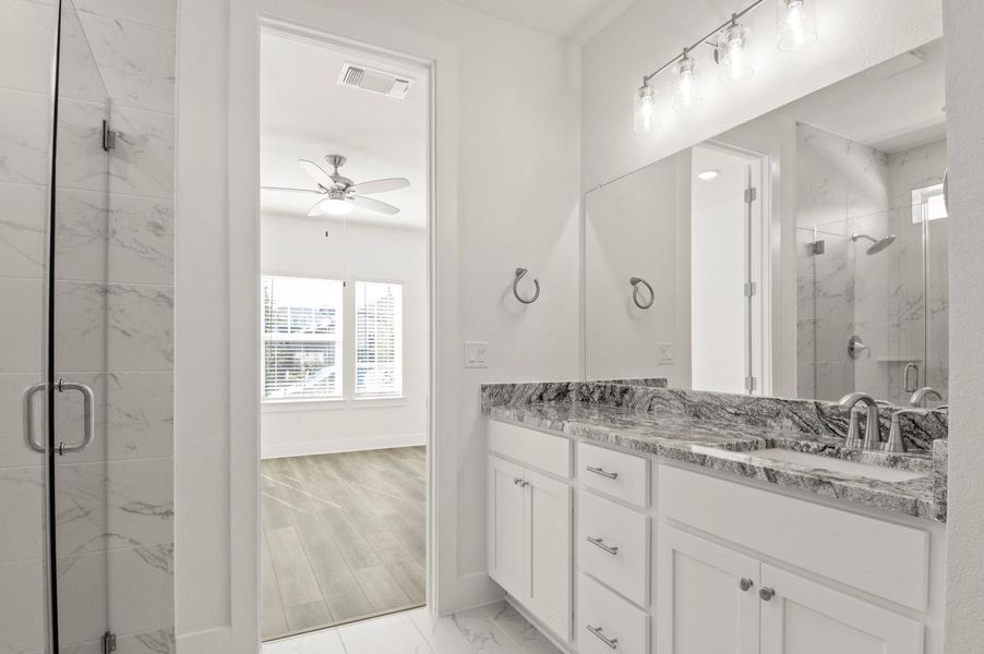 Bathroom featuring a marble finish shower, double vanity, and ceiling fan Bathroom featuring a marble finish shower, double vanity, and ceiling fan