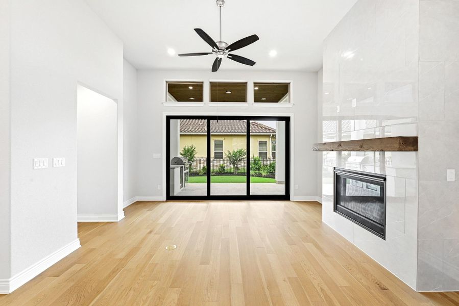 Expansive living space featuring wood-finish flooring, a modern fireplace with a substantial mantel, and a multi-panel sliding glass door