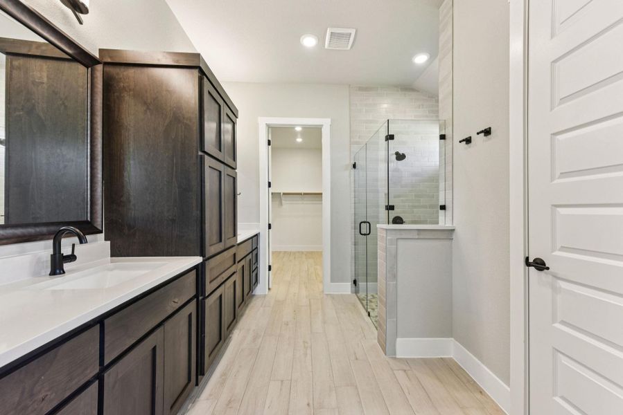 Full bathroom featuring a walk in closet, vanity, light wood-type flooring, a stall shower, and recessed lighting