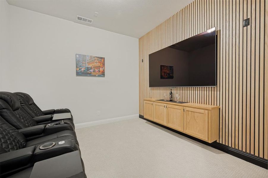Dedicated media room featuring a striking wood accent wall, custom built-in cabinetry, and ample space for theater seating. The perfect setting for movie nights, game days, or streaming your favorite shows in style and comfort. Dedicated media room featuring a striking wood accent wall, custom built-in cabinetry, and ample space for theater seating. The perfect setting for movie nights, game days, or streaming your favorite shows in style and comfort.