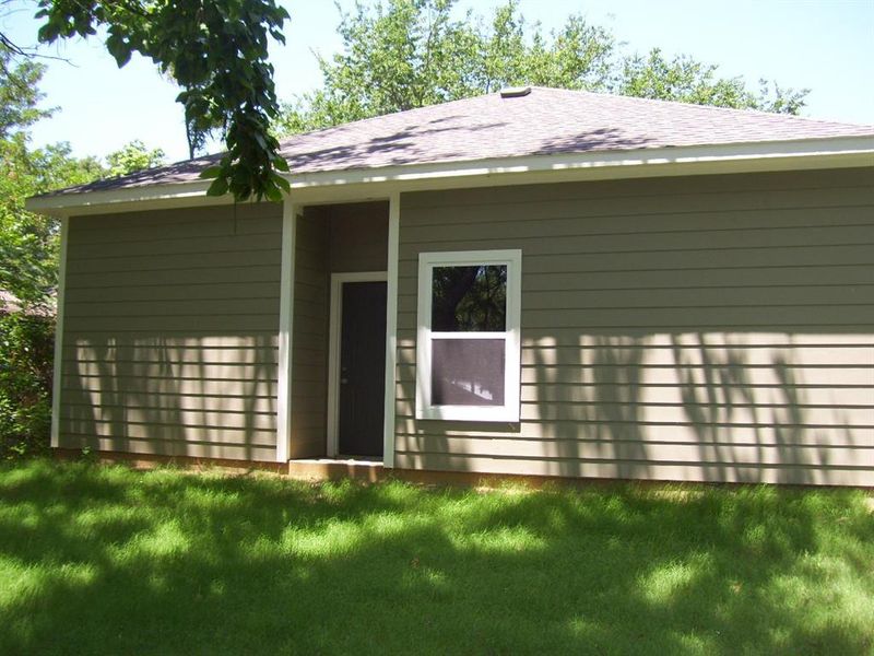 Rear view of house with a lawn and roof with shingles