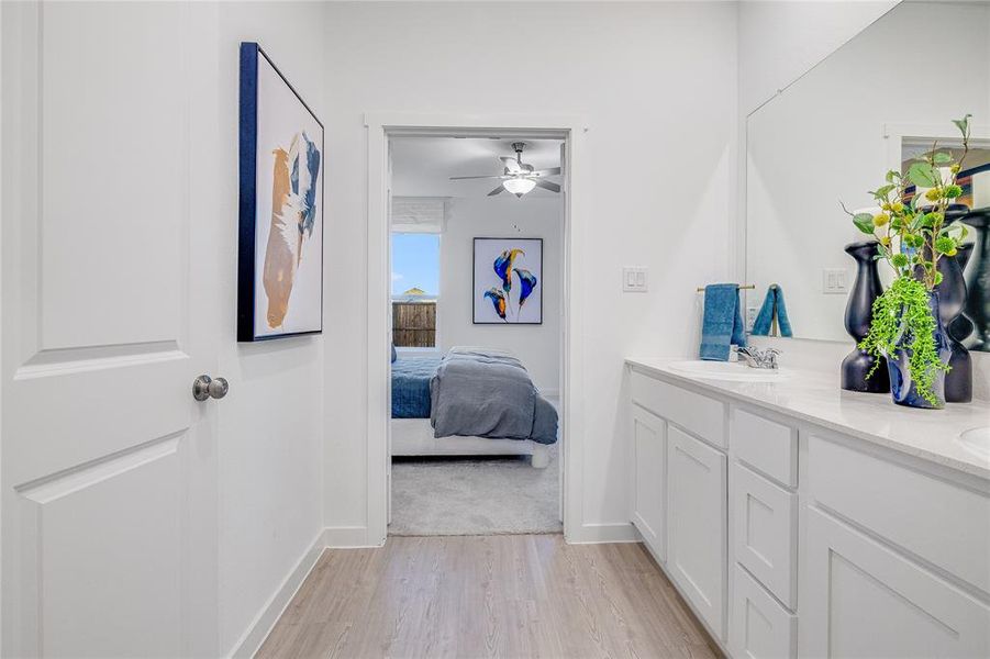 Ensuite bathroom featuring double vanity, a sink, ensuite bath, wood finished floors, and baseboards