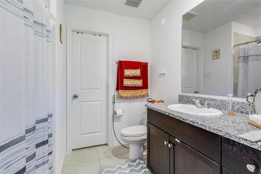 Full bath featuring a shower with curtain, vanity, and light tile patterned floors