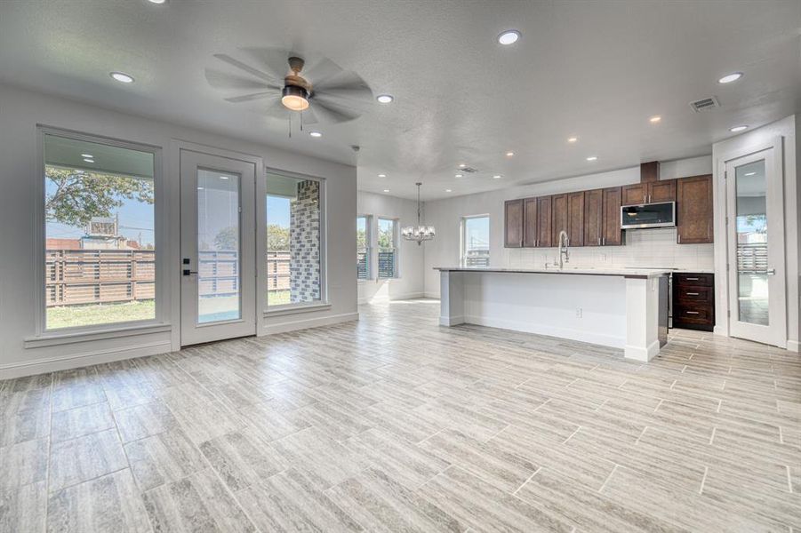 Unfurnished living room featuring sink and ceiling fan with notable chandelier