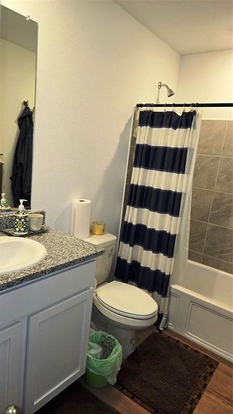 Bathroom vanity with a white basin, speckled countertop, and white cabinetry