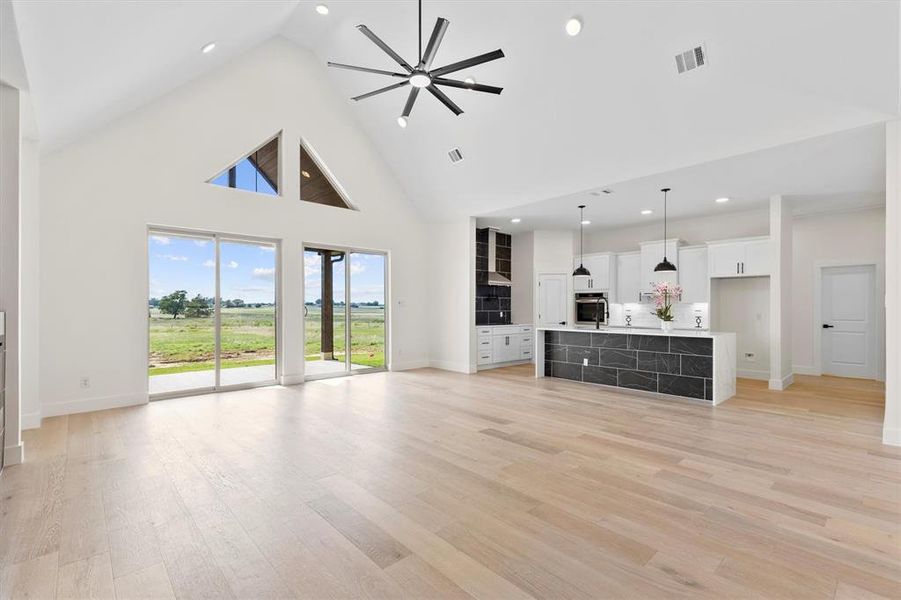 living room with high vaulted ceiling, baseboards, light wood-style flooring, recessed lighting, and a ceiling fan living room with high vaulted ceiling, baseboards, light wood-style flooring, recessed lighting, and a ceiling fan