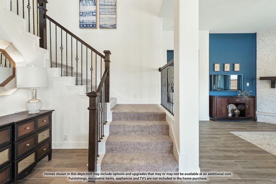 Carpeted staircase with dark wood and iron railings in a two-story foyer with wood-look tile floors Carpeted staircase with dark wood and iron railings in a two-story foyer with wood-look tile floors
