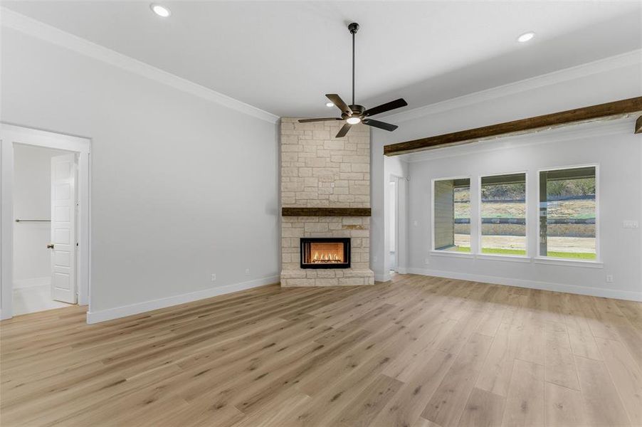 Unfurnished living room featuring crown molding, light wood finished floors, ceiling fan, a fireplace, and recessed lighting