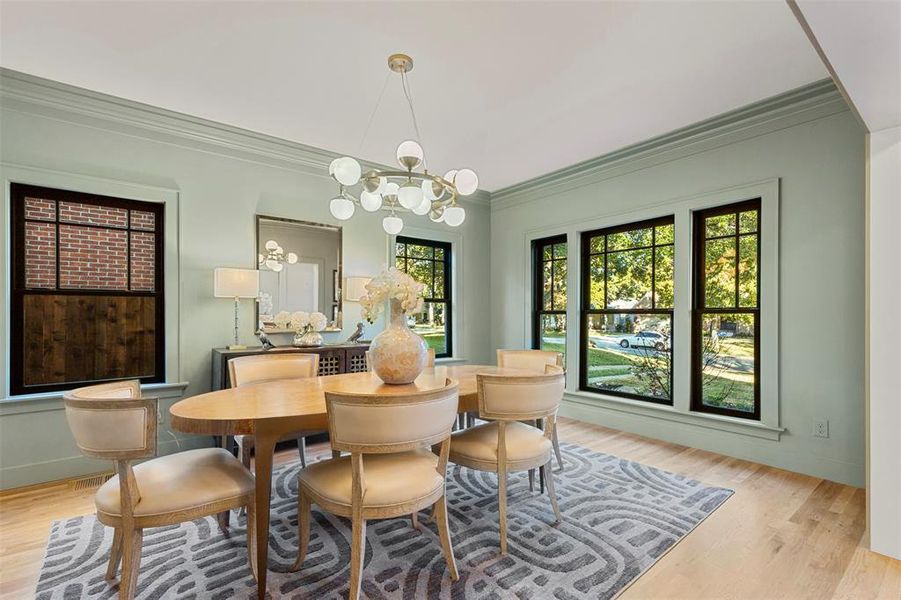 Dining space with a notable chandelier, light hardwood / wood-style flooring, and crown molding