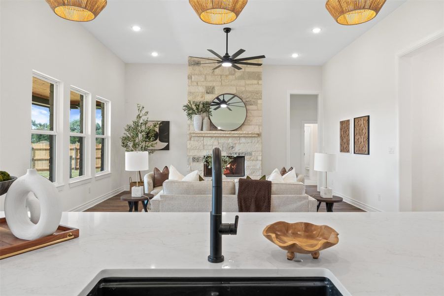 Kitchen with light stone countertops, wood finished floors, a fireplace, ceiling fan, and recessed lighting Kitchen with light stone countertops, wood finished floors, a fireplace, ceiling fan, and recessed lighting