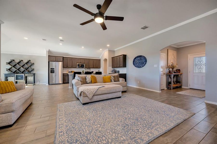 Living area featuring ornamental molding, arched walkways, wood tiled floors, a ceiling fan, and recessed lighting