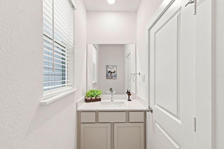 Bright and stylish powder room featuring a modern vanity, quartz countertop, large mirror, and natural light. Bright and stylish powder room featuring a modern vanity, quartz countertop, large mirror, and natural light.