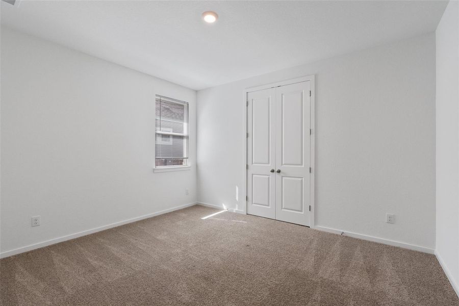A spacious, naturally illuminated room featuring plush carpet and ample storage with its double-door closet.