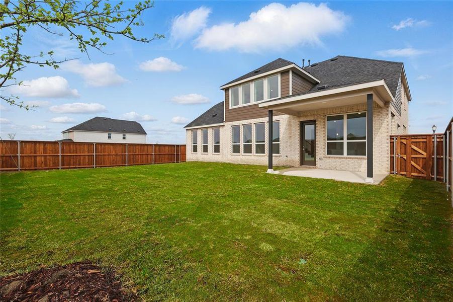 Back of house featuring roof with shingles, a patio, a fenced backyard, brick siding, and a lawn