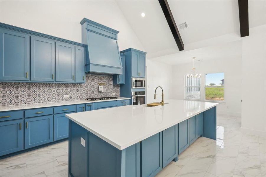 Kitchen featuring beam ceiling, a large island with sink, a chandelier, and appliances with stainless steel finishes