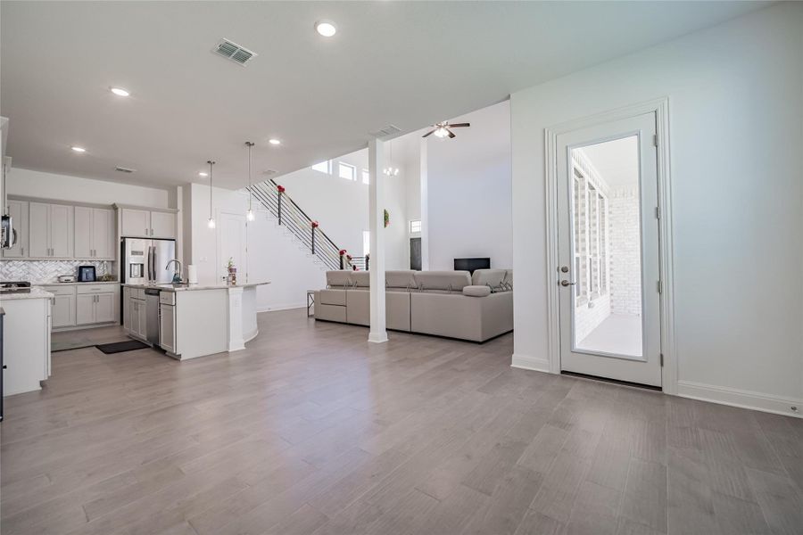 An airy great room seamlessly blends a modern kitchen with a comfortable living space, featuring high ceilings.