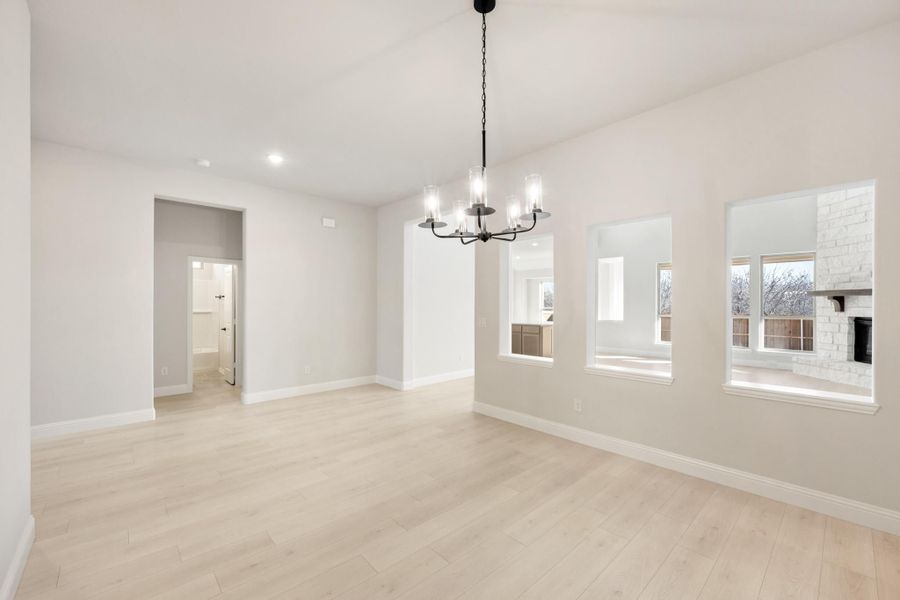 Open dining area with light wood floors, black chandelier, and large windows