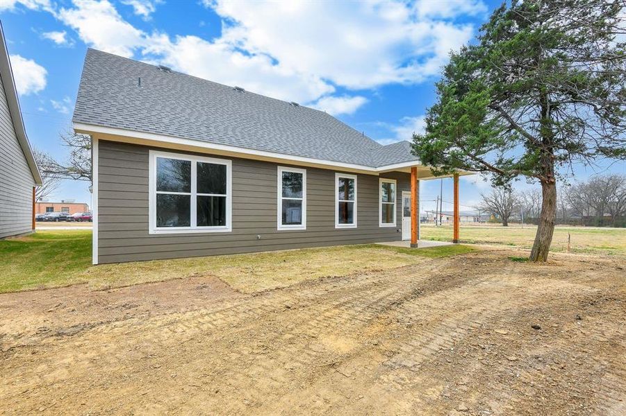 Back of house featuring roof with shingles and a patio area