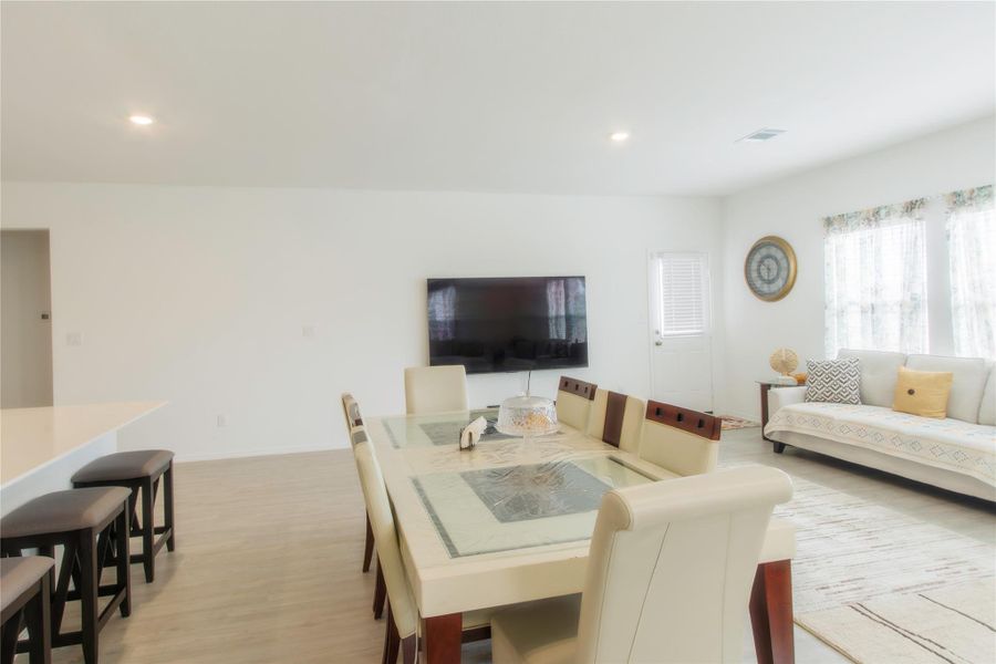 Bright and airy living room featuring large windows, wood-style floors, and recessed lighting, perfect for both relaxing and hosting guests.