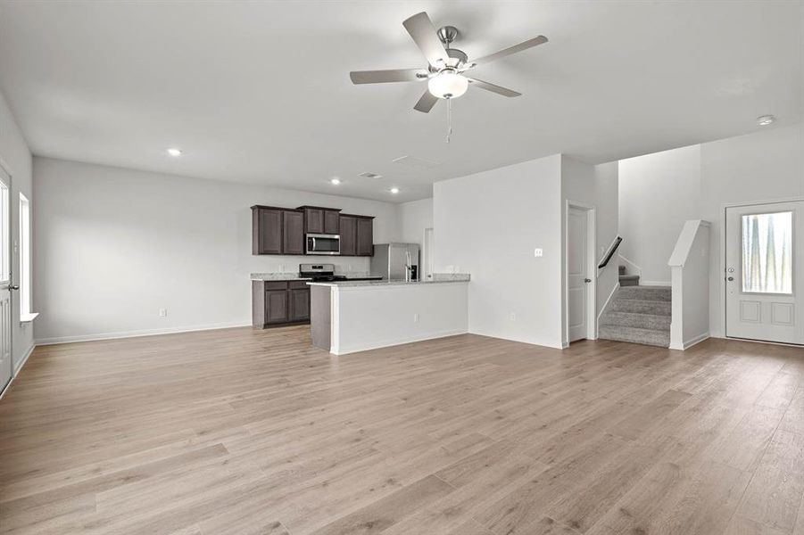 Unfurnished living room with light wood-style flooring, a ceiling fan, stairway, and recessed lighting