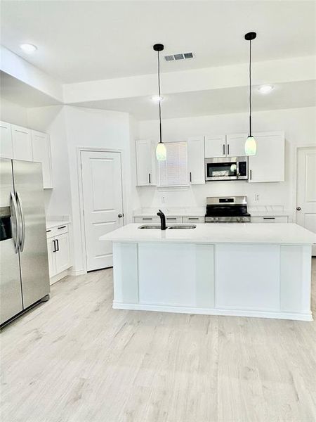 Kitchen with white cabinetry, stainless steel appliances, decorative light fixtures, and recessed lighting