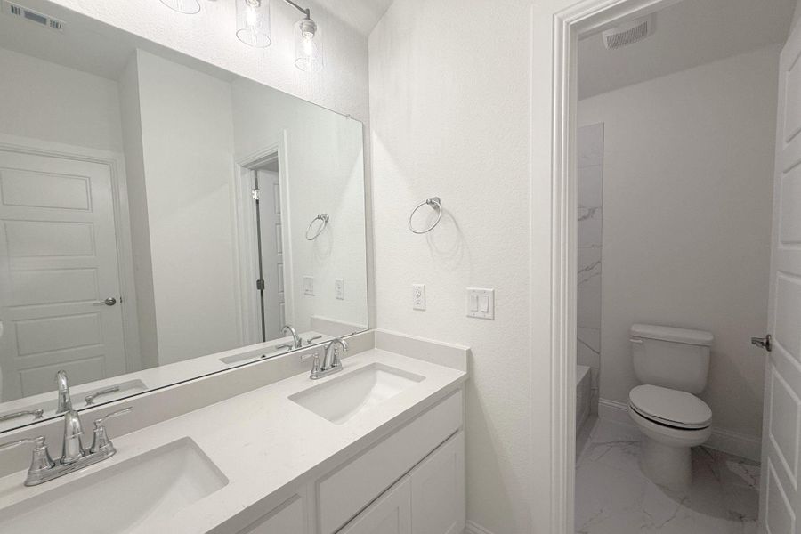 Bathroom with dual vanity featuring integrated sinks, light countertops, and chrome fixtures