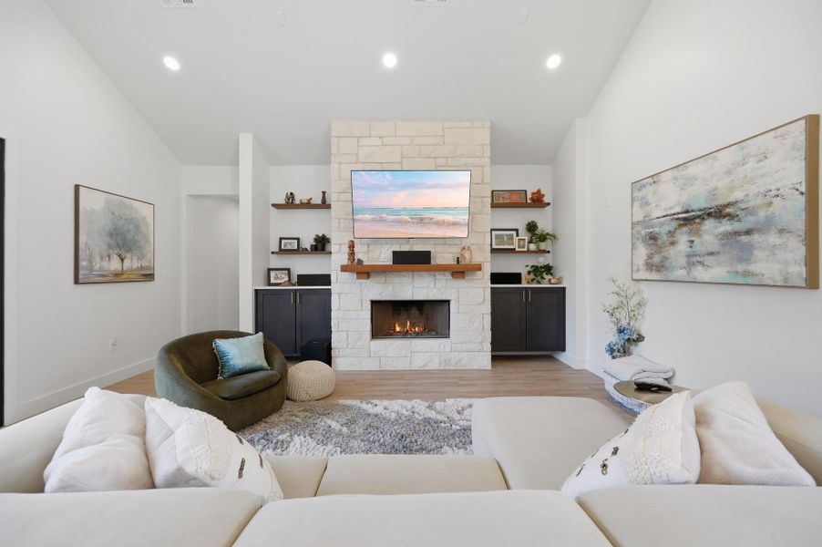 A stone fireplace anchors the living space under vaulted ceilings with recessed lighting.