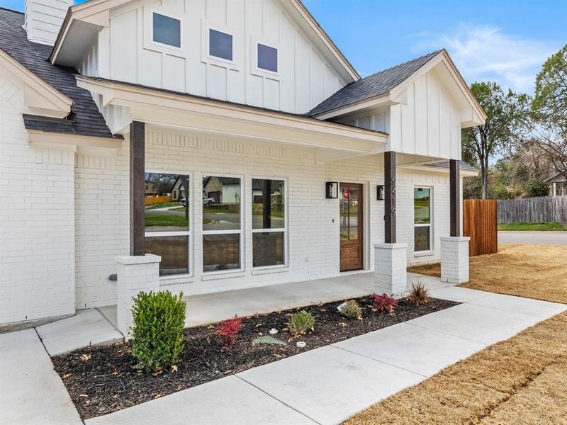 Doorway to property with fence, brick siding, board and batten siding, and roof with shingles