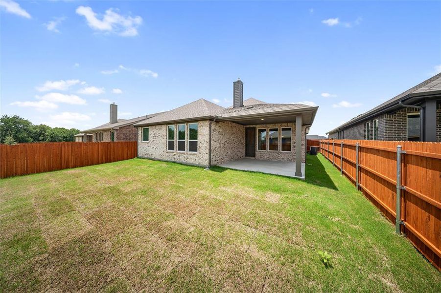 Back of house with a chimney, brick siding, a fenced backyard, and a patio area
