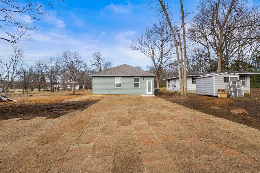 Back of property featuring an outbuilding and a shingled roof