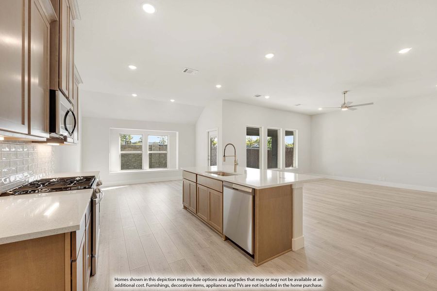 Open kitchen with wood cabinets, center island with sink, stainless appliances, and light hardwood floors opening to living area. Open kitchen with wood cabinets, center island with sink, stainless appliances, and light hardwood floors opening to living area.