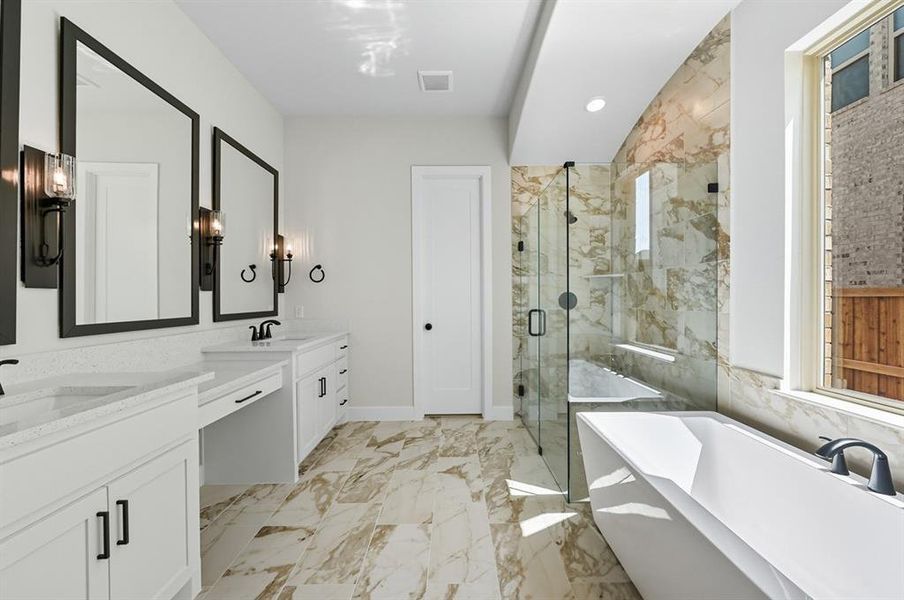 Full bath featuring a marble finish shower, a freestanding bath, two vanities, recessed lighting, and light marble finish flooring