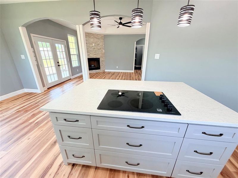 Kitchen island with built-in cooktop, light-toned countertop, and ample drawer storage