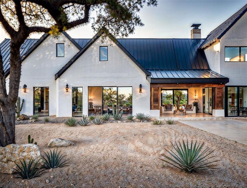 Back of house featuring a patio, a standing seam roof, stucco siding, a chimney, and metal roof