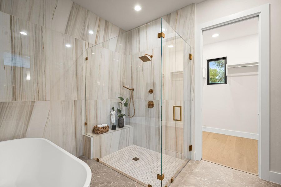 Full bath featuring a freestanding tub, marble tiled floors, a walk in closet, a stall shower, and recessed lighting
