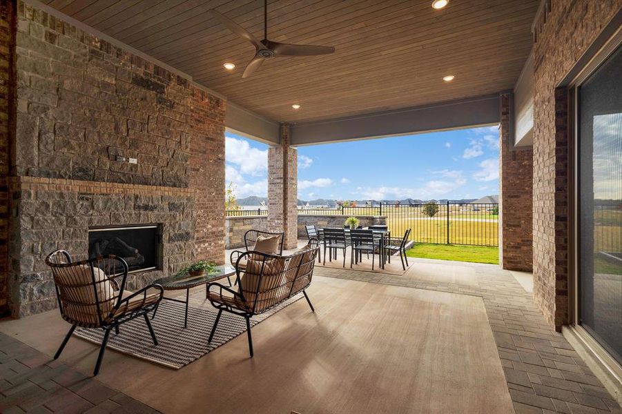 View of patio / terrace featuring an outdoor stone fireplace, outdoor dining space, and ceiling fan