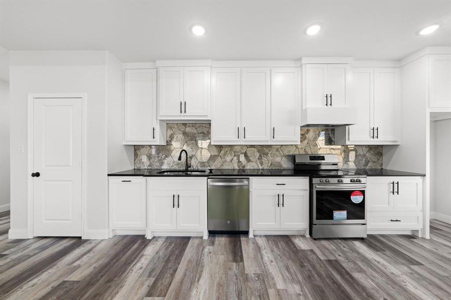 Kitchen with appliances with stainless steel finishes, dark countertops, white cabinetry, decorative backsplash, and recessed lighting Kitchen with appliances with stainless steel finishes, dark countertops, white cabinetry, decorative backsplash, and recessed lighting