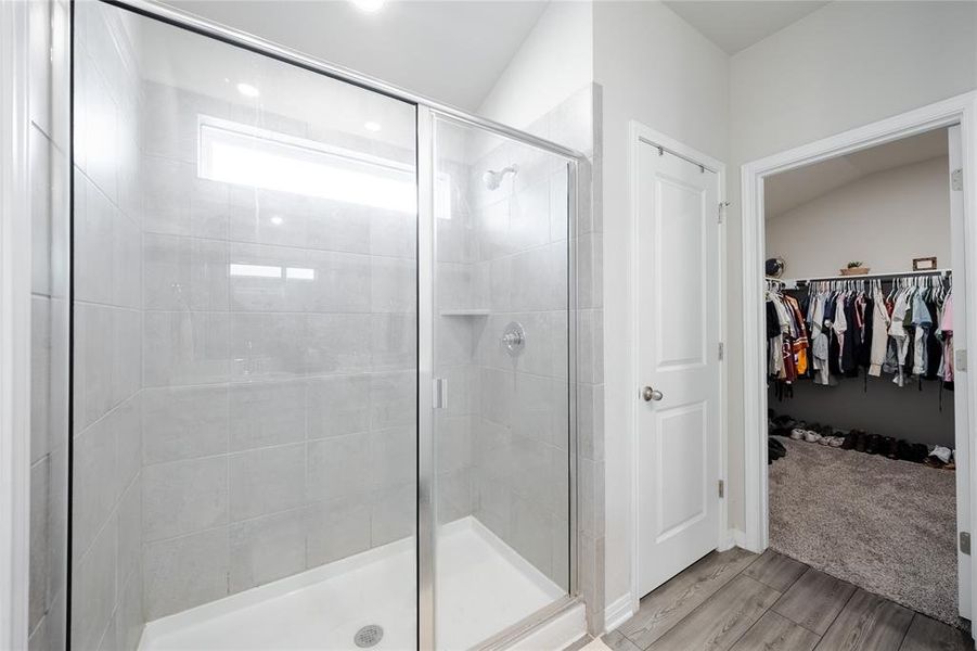 Bathroom featuring a stall shower, a walk in closet, and light wood-type flooring