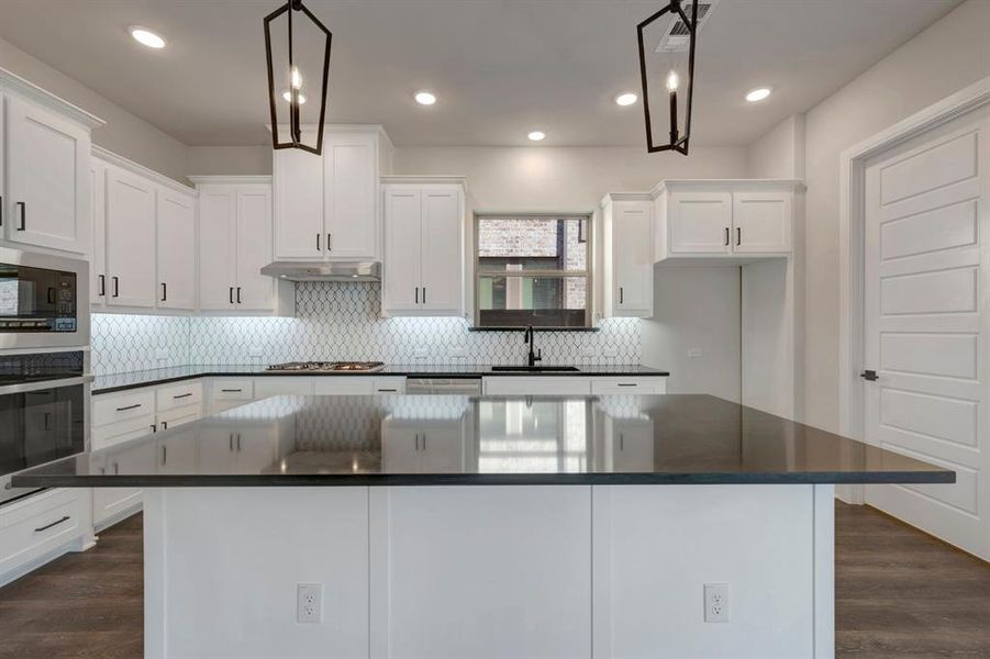 Kitchen with a kitchen island, dark wood-style floors, white cabinetry, stainless steel appliances, and backsplash