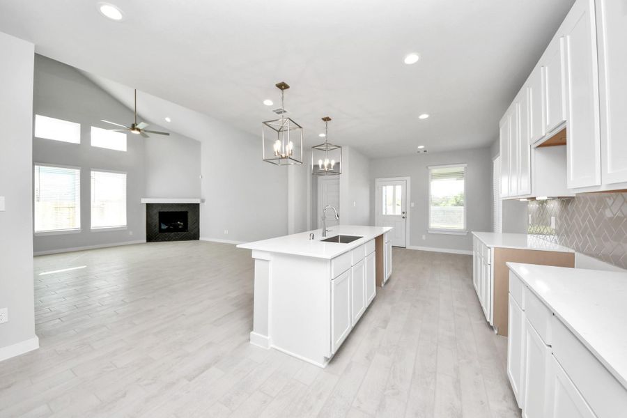 This kitchen is truly a chef's dream! This haven Boasts high ceilings, recessed & pendant lighting, stained wood cabinets, granite countertops, stainless steel appliances, a modern tile backsplash.  All of this overlooks your expansive family room, creating a perfect space for culinary delights and family gatherings. Sample photo of completed home with similar floor plan. Actual colors and selections may vary.